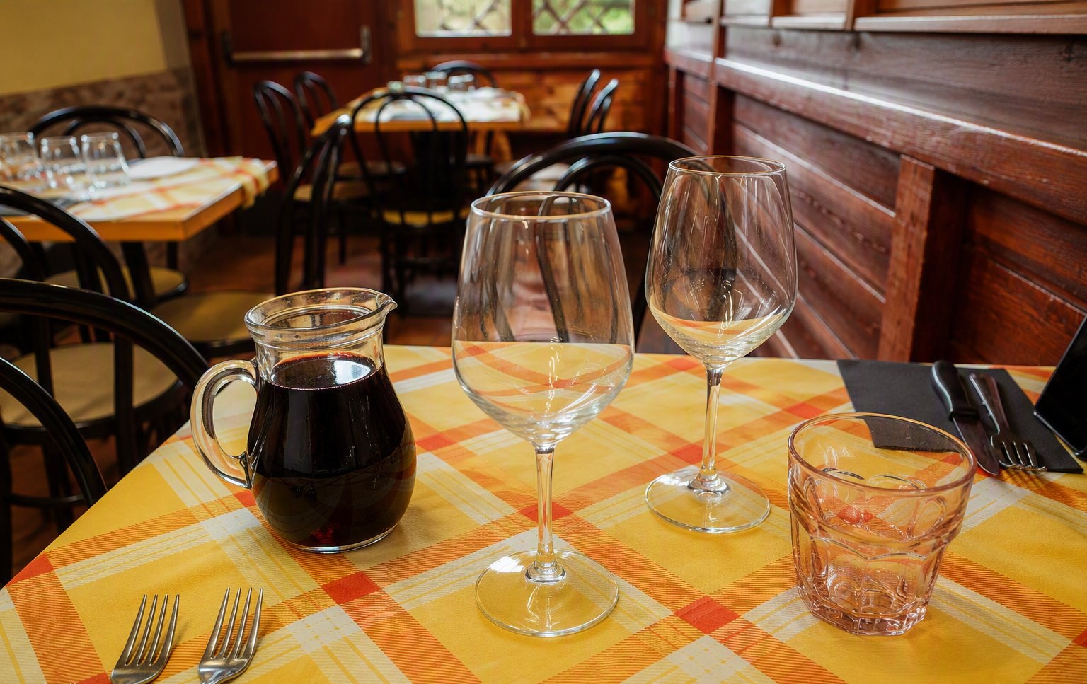 Il tavolo apparecchiato con la tovaglia a quadri e la brocca di vino